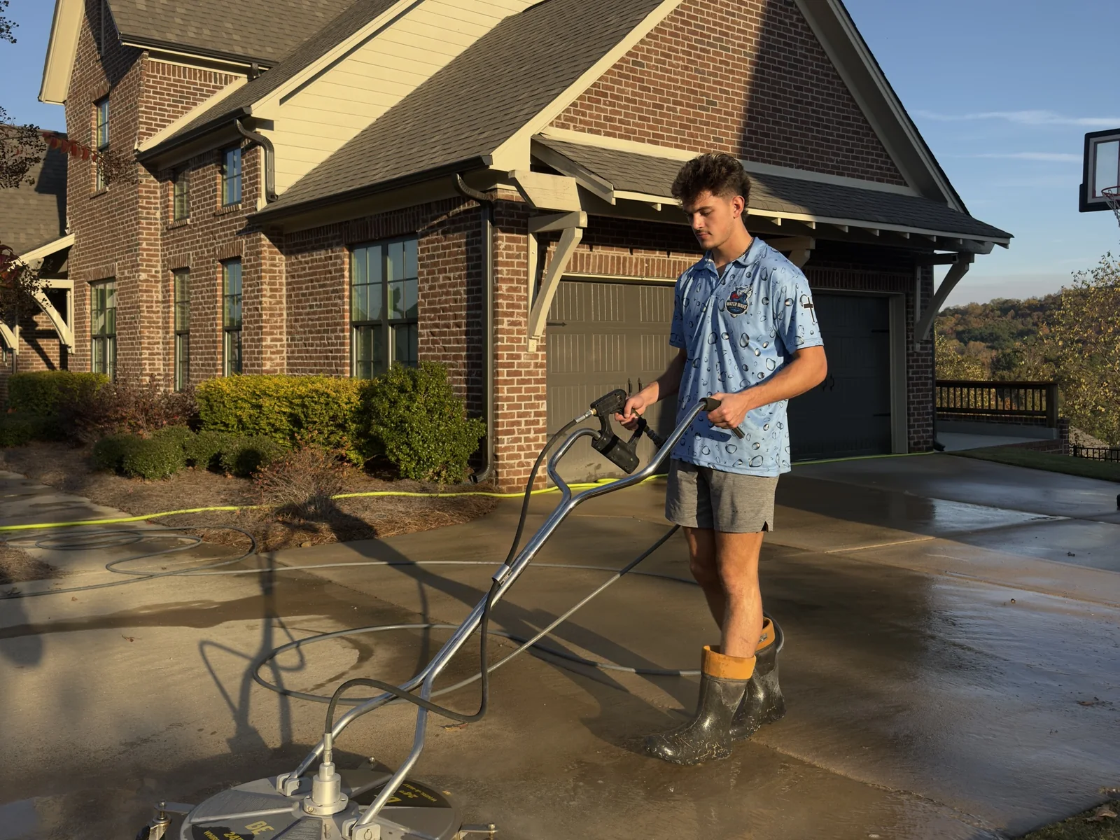 Water Wave team member pressure washing a driveway with a surface cleaner